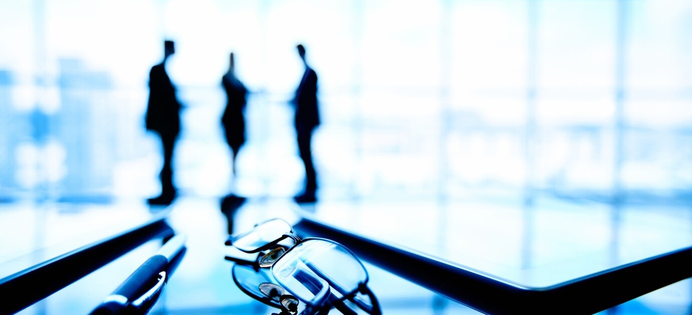 Close-up view of a negotiating table with hands of business professionals, documents, and a pen in focu
